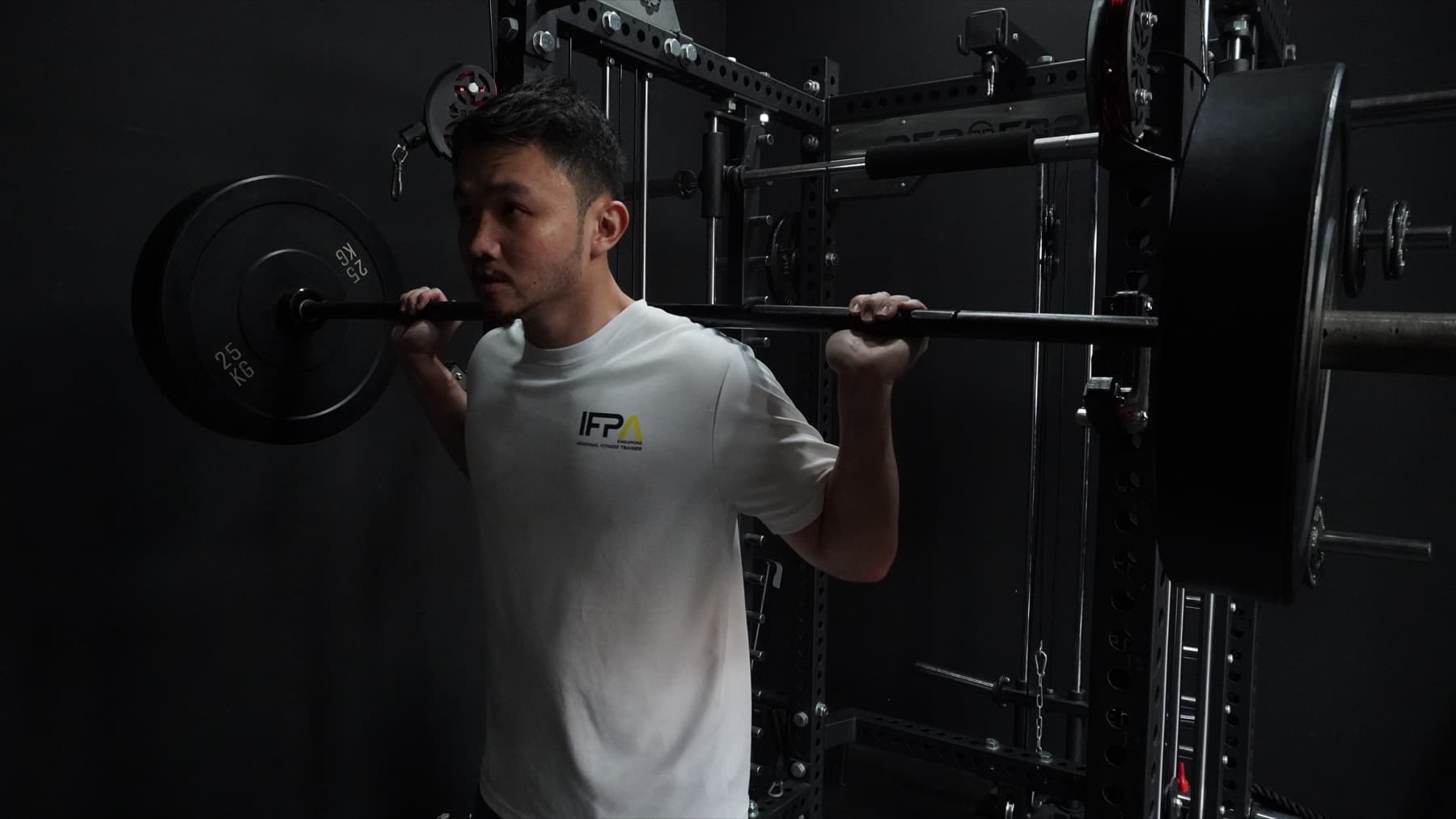 Coach spotting a learner during a barbell squat at an IFPA PFT practical session